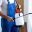 Pest control technician spraying indoor treatment near windows and baseboards in {city}, {state}